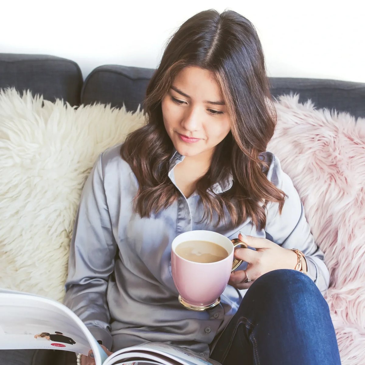 Woman reading on a cozy couch with a cup of coffee